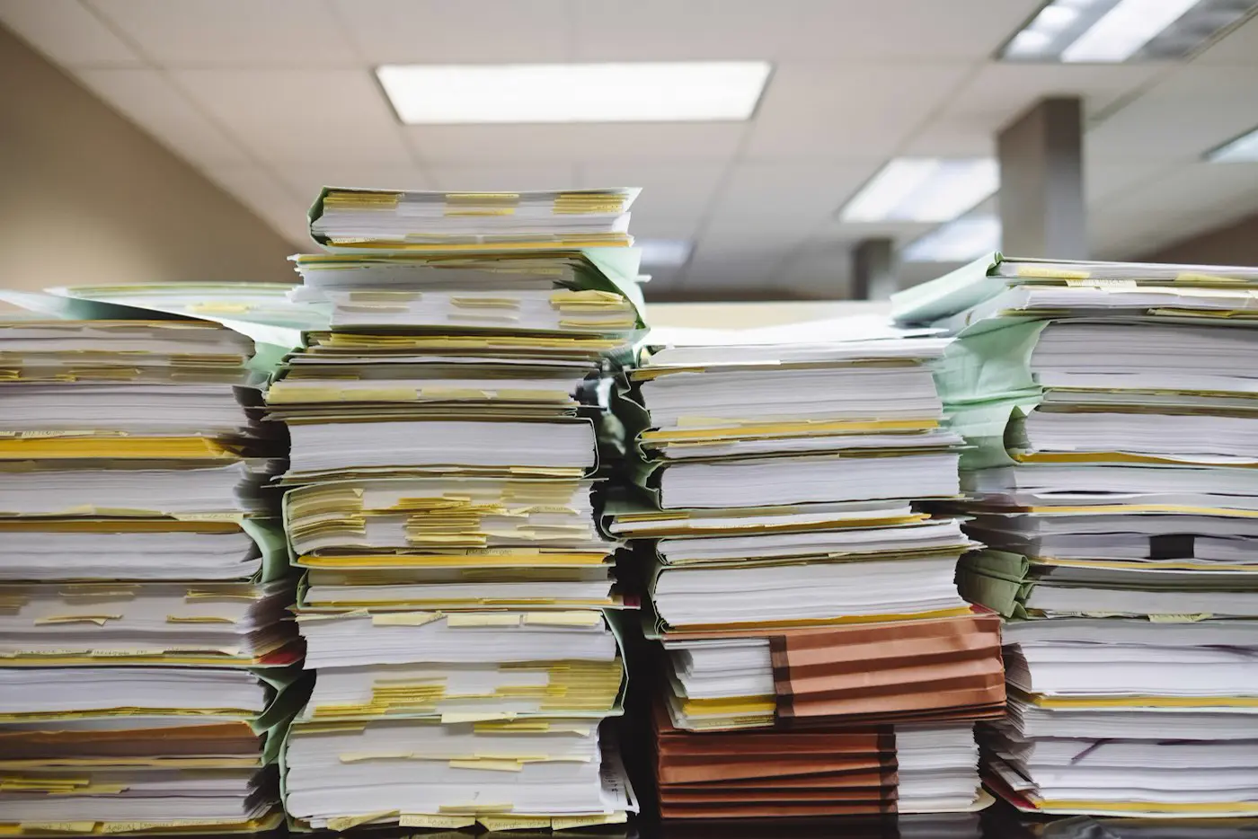 Pilas de carpetas y documentos en papel acumulados en una oficina